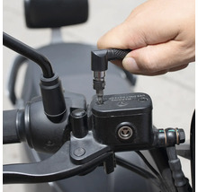 Une personne utilise un tournevis avec embout coudé pour travailler sur une moto.