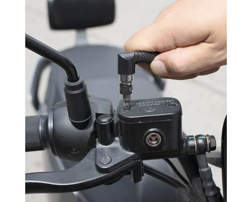 Une personne utilise un tournevis avec embout coudé pour travailler sur une moto.
