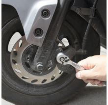 Une personne utilise un cliquet sur une moto.