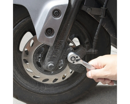Une personne utilise un cliquet sur une moto.