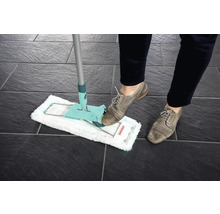 Serpillère en utilisation sur des carreaux sombres, actionnée par une personne chaussée.