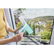 Femme utilisant un lave-vitre avec une housse en microfibre pour nettoyer une fenêtre