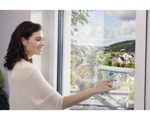 Une femme nettoie les fenêtres avec un lave-vitre pour une propreté sans traces