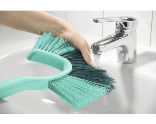 Hand unter Wasserhahn beim Auswaschen einer Bürste im Waschbecken