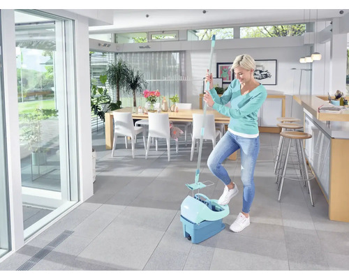Frau putzt mit einem Mopp und Eimer einen hellen Raum.