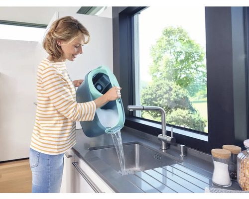 Frau leert Eimer mit Reinigungsmittel in ein Spülbecken