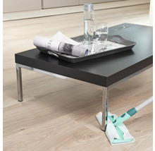 Scène d''une personne nettoyant un plancher en bois avec une serpillière, avec une table sombre et des boissons dessus.