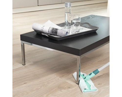 Scène d''une personne nettoyant un plancher en bois avec une serpillière, avec une table sombre et des boissons dessus.