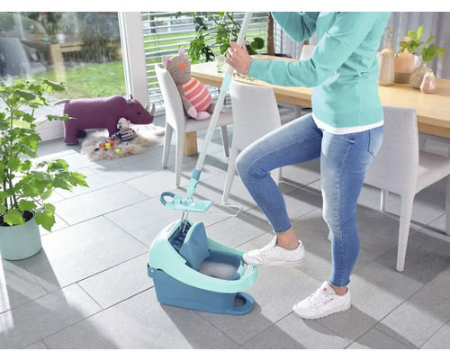 Femme utilise un balai à franges et un seau pour nettoyer le sol