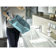 Femme vide un seau polyvalent dans un lavabo dans la salle de bain
