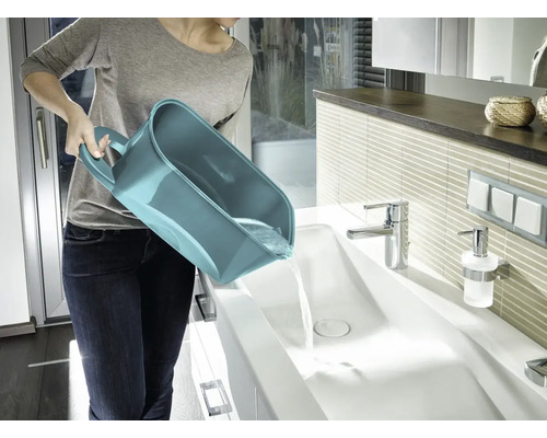 Femme vide un seau polyvalent dans un lavabo dans la salle de bain