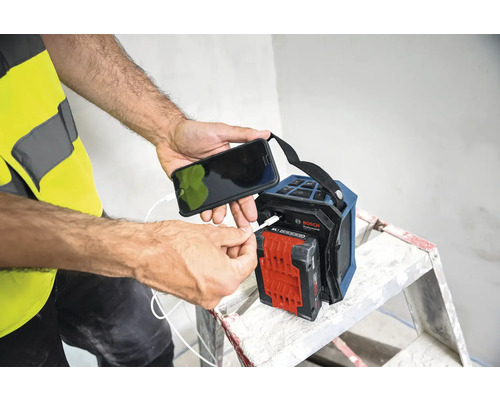 Une personne recharge un téléphone portable sur une radio de chantier Bosch.