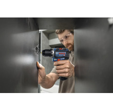 Handwerker befestigt mit einem Akku-Bohrschrauber ein Scharnier an einer Tür.