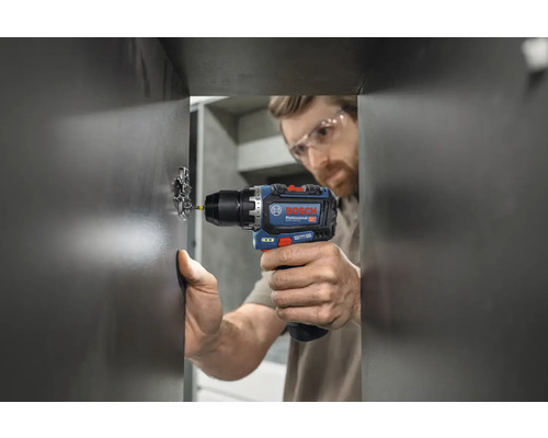 Handwerker befestigt mit einem Akku-Bohrschrauber ein Scharnier an einer Tür.