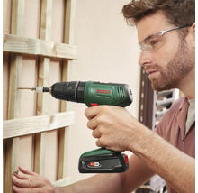 Un homme visse une vis dans une construction en bois avec une visseuse à percussion sans fil Bosch