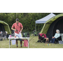 Scène de camping avec une personne faisant la vaisselle, des tentes et des sièges