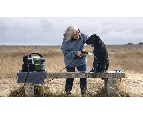 Femme lavant un chien avec un nettoyeur haute pression portable Bosch en extérieur.