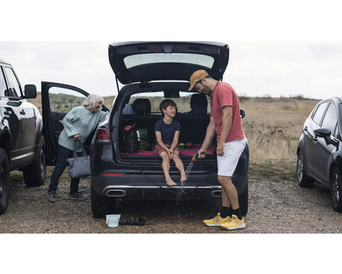 Scène avec une famille se nettoyant les pieds avec un tuyau d'arrosage après une excursion en plein air.