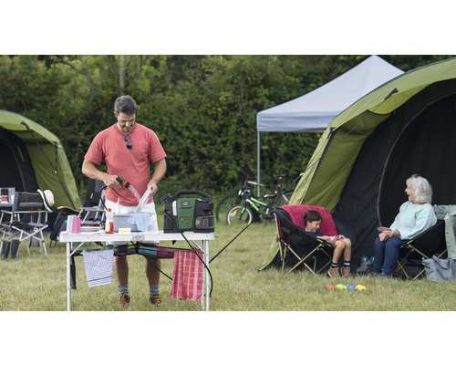 Scène de camping avec un homme faisant la vaisselle, des tentes et des activités de loisirs