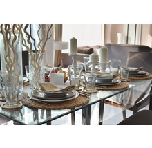 Table à manger dressée de manière festive avec vaisselle, verres, bougies et décoration