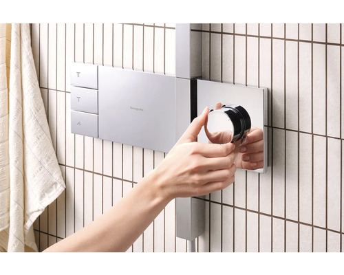 Person bedient Hansgrohe Duscharmatur im Badezimmer.