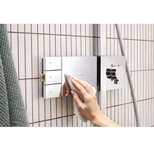 Hand reinigt Duscharmatur von Hansgrohe im Badezimmer.