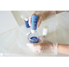 Une personne mélange de la peinture de résine de coulée bleue dans un récipient en verre pour des projets artistiques.