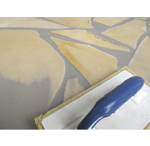 Des carreaux de mosaïque sont appliqués à l'aide d'une truelle à joint