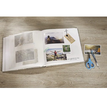 Album photo ouvert avec des photos collées, un stylo et des ciseaux sur une table