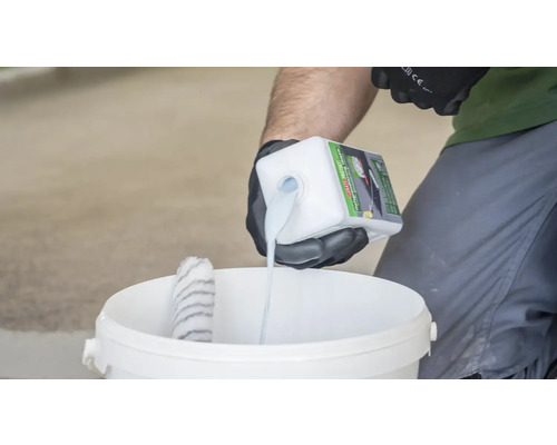 Eine Person giesst Grundierung in einen Eimer zum Auftragen mit einer Farbwalze.