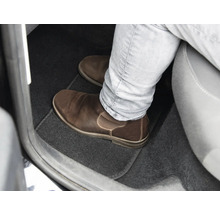 Fußraum eines Autos mit Fußmatte und Lederschuh