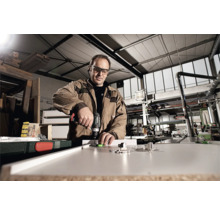 Mann arbeitet mit Akku-Bohrschrauber an Werkstück in Werkstatt