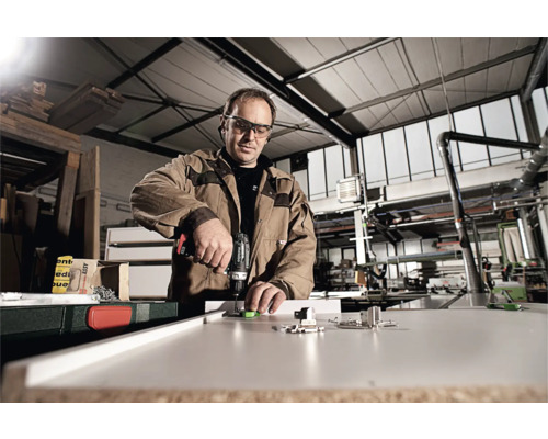 Mann arbeitet mit Akku-Bohrschrauber an Werkstück in Werkstatt