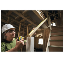 Une femme mesure du bois avec un mètre ruban Stanley sur un chantier.