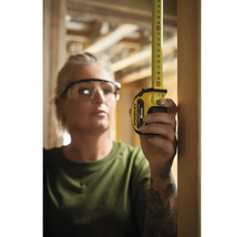 Femme mesure avec un mètre ruban Stanley 8 m.