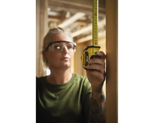 Femme mesure avec un mètre ruban Stanley 8 m.