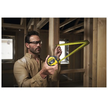 Un homme mesure avec un mètre à ruban Stanley de 8 m dans une construction brute.