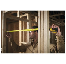 Un artisan mesure avec un mètre ruban dans une construction brute