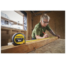 Femme mesurant du bois avec un mètre ruban Stanley de 8 mètres de long