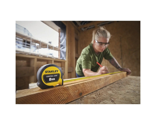 Femme mesurant du bois avec un mètre ruban Stanley de 8 mètres de long