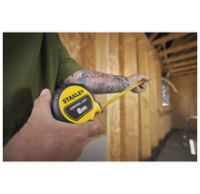 Une personne mesure une pièce avec un mètre ruban Stanley.