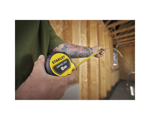 Une personne mesure une pièce avec un mètre ruban Stanley.