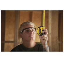 Femme mesurant une planche de bois avec un mètre ruban Stanley