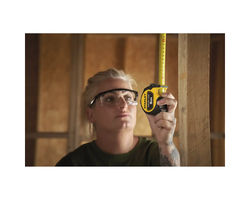 Femme mesurant une planche de bois avec un mètre ruban Stanley