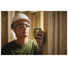 Une femme mesure avec un mètre ruban Stanley de 8 m dans une construction à ossature bois