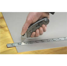 Main coupant un matériau avec un cutter Stanley et une règle