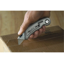 Une main coupe un carton avec un cutter Stanley.