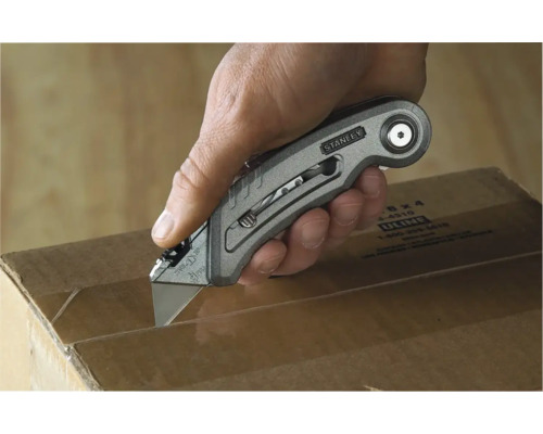 Une main coupe un carton avec un cutter Stanley.