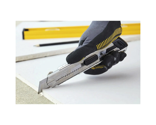 Eine Hand mit Arbeitshandschuh schneidet mit einem Cuttermesser eine Gipskartonplatte.