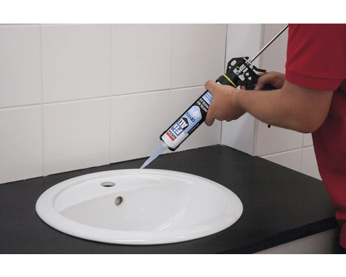 Application de la colle cristal Soudal Fix All avec un pistolet à cartouche sur un lavabo